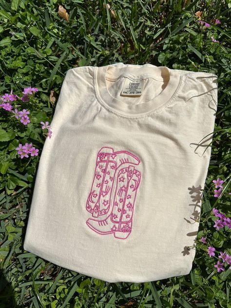 Our Cowgirl Boots Embroidered Tee is sure to turn a lot of heads. This t-shirt provides a soft and cozy feel, making it perfect for any occasion. It is made on comfort colors material t-shirt. To make your customization process seamless, please include your desired shirt size and shirt color on the drop down options above. Please make sure to include your personalization on what you are wanting in the box above.  You can also add thread color for your shirt, please make sure to make a selection Boots Embroidered, Embroidered Shirts, T-shirt Broderie, Looks Country, Western Style Outfits, Cowgirl Shirts, Wedding 2025, Embroidered Tee, Embroidered Crewneck