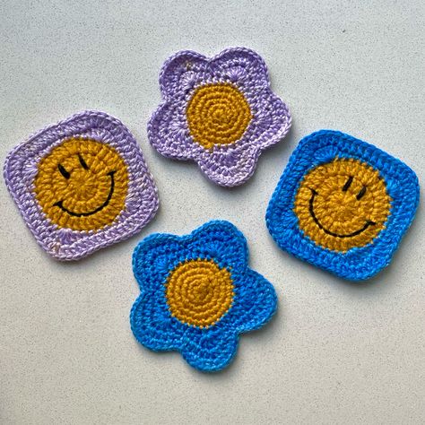 Four crochet coasters, two flowers, on with blue petals and yellow middle, other with lilac petals and a yellow middle. Other two are smiley faces with a blue square border and a lilac square border. Groovy Crochet, Hippie Home Decor, Maximalist Decor, Crochet Home Decor, Crochet Applique, Crochet Coasters, Crochet Home, Crochet Animals, Creative Inspiration