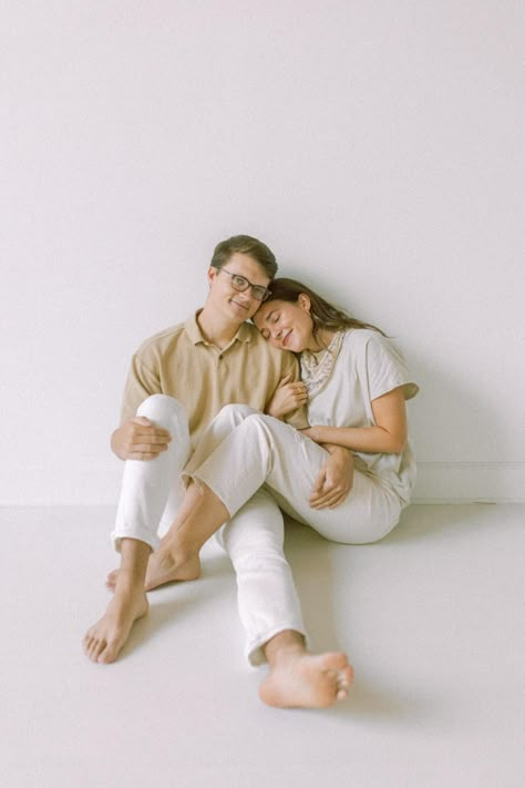 couple-sitting-in-white-studio-in-atlanta-Georgia-with-neutral-outfits-on-cuddling-with-arms-wrapped-around-each-other-and-softly-smiling Engagement Studio Photo, Studio Mini Sessions, Prenup Shoot, Minimal Monochrome, Studio Photoshoot Ideas, Couples Outfits, Couple Sitting, Neutral Outfits, Studio Poses