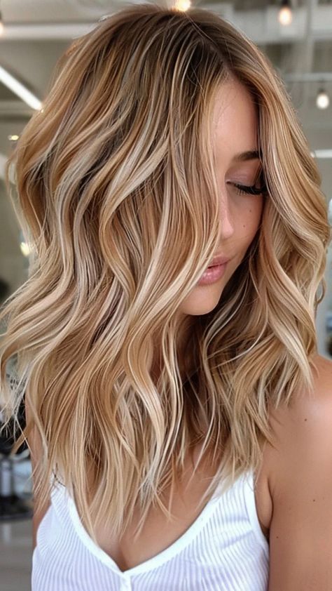 Woman with wavy blonde hair highlights, wearing a white top, in a modern salon. Brown Hair After Red, Cherry And Blonde Highlights, Strawberry Hair Color Blonde, Blonde And Auburn Highlights On Brown Hair, Low Maintenance Winter Blonde, Copper Babylights On Blonde Hair, Dark Blonde Hair With Red Undertones, Brunette With Blonde And Red, Blonde Hair Color Ideas With Lowlights