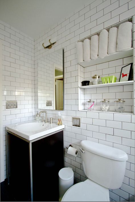 Amazing bathroom with niche filled with shelves above toilet next to black washstand with white porcelain sink paired with frameless mirror and white subway tiles with black grout. Bathroom With Niche, Bathroom Storage Over Toilet, Above Toilet, Shelves Above Toilet, Bathroom Niche, Storage Vanity, Recessed Shelves, Shelves Over Toilet, Bathroom Shelves Over Toilet