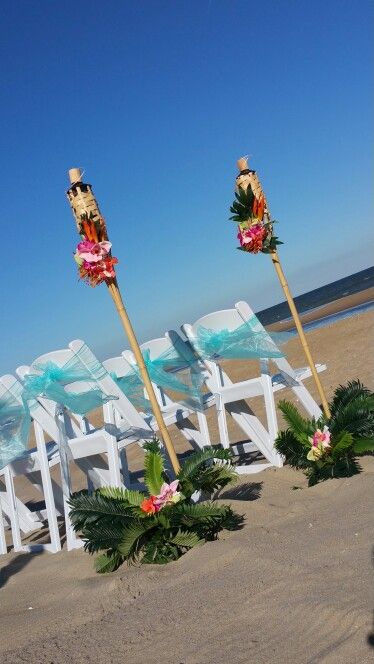 Tiki torches and Aqua blue beach wedding decor. Barefootbeachbrideoc.com Tiki Torches Wedding, Tiki Torch Wedding, Tiki Torch Wedding Aisle, Tropical Aisle Markers, Liquor Bottle Tiki Torch Diy, Citronella Tiki Torch, Blue Beach Wedding, Outside Plants, Tiki Torches