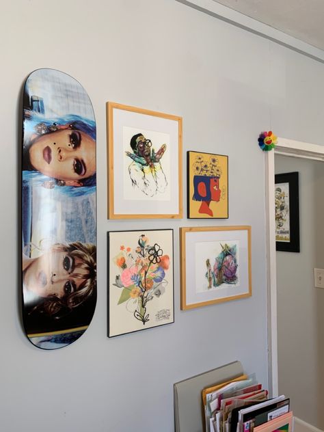 A skateboard hanging on a wall with 4 other art prints assembled into a gallery wall. The art prints have different flower imagery. Skateboard On Wall, Skate Deck Decor, Skateboard Decor Ideas, Skate House Decor, Gallery Wall With Skateboard, Danish Eclectic, Skateboard Wall Decor, Skateboard Decor Ideas Wall Art, Skateboard On Wall Decor