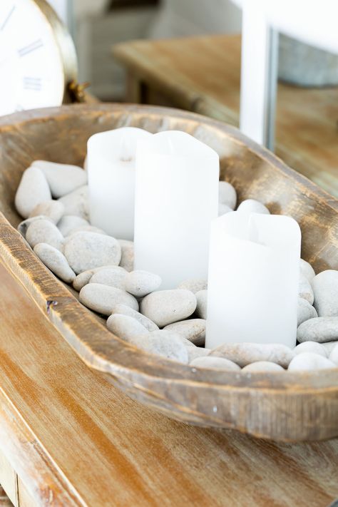 Fill a dough bowl with white river rocks and candles. Boho Dough Bowl Decor, Bowl Of Rocks Decor, Styling A Wooden Bread Bowl, Coastal Dough Bowl Decor, Large Dough Bowl Centerpiece, Simple Dough Bowl Decor, Decorative Dough Bowl Ideas, Dough Bowl Candle Decor, White Bowl Centerpiece Ideas