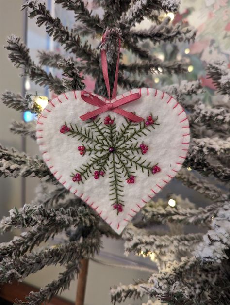 Wool Felt Heart/Valentine Ornament This charming hand stitched wool felt heart comes together with pine boughs and deep pink beads. It will be the perfect addition for your home decor. The stitching is done free hand, and it is likely no two pine boughs are the same nor is the placement of the beads. The star measures approximately 4 inches wide and 4.25 inches tall. The heart has a pink ribbon bow and hang loop with pink border stitch. Find more wool felt designs here: https://www.etsy.com/listing/1645915226/wool-felt-heart-picks-valentine-hearts?ref=listings_manager_table https://www.etsy.com/listing/1656982989/gift-card-mitten-ornaments-gift-card?ref=listings_manager_table https://www.etsy.com/listing/1454723524/shasta-daisy-table-runner-flower-table?ref=listings_manager_table Threadsan Felt Heart Embroidery, Pink Felt Christmas Ornaments, Pink Felt Ornaments, Heart Felt Ornaments Diy, Felt Christmas Hearts, Felt Heart Ornaments, Sew Heart Ornament, Daisy Table, Felt Embroidered Heart Ornaments