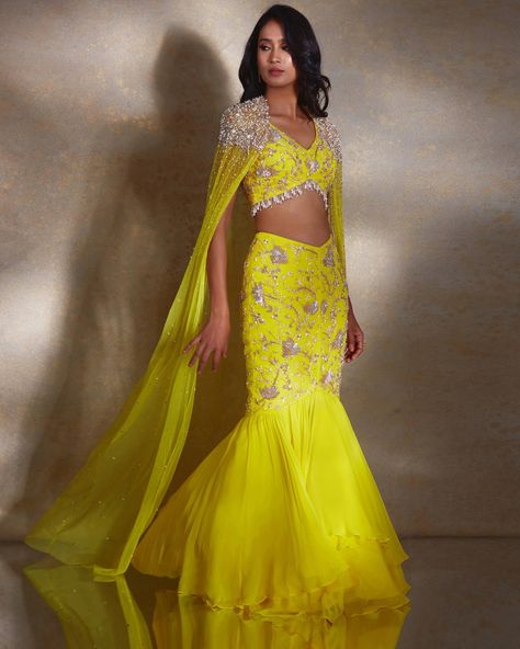 Shop this ariel Skirt Set by Shloka Khialani at KYNAH. The ariel ensemble is perfect for making a statement at any special event. The sleeveless yellow blouse is embellished with silver and champagne daffodils, and paired with a flattering fishtail skirt and sheer georgette layer. A net cape hand embellished with pearls, glass beads, and tassels completes the look. Tassel Skirt Outfit, Latest Bridal Lehenga Designs, Beads Tassels, Haldi Outfits, Haldi Outfit, Bridal Lehenga Designs, Latest Bridal Lehenga, Indian Outfits Lehenga, Tassel Skirt