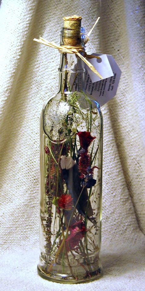 Dried flowers fill this clear wine bottle. Clear Bottle Decor, Clear Wine Bottle Crafts, Dried Flowers In A Bottle, Wine Bottle With Flowers Inside, Dried Flowers In Wine Bottle, Alcohol Bottle Decor, Wine Bottle Vase Flowers, Wine Bottles With Flowers, Bottle Filler Ideas