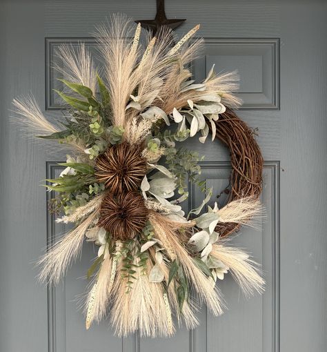 This beautiful fall wreath will be the perfect touch for your door, double doors, columns, wall, etc. Wreath is made on a grapevine base and packed full of quality faux pampas, eucalyptus, lambs ear, vine pumpkins and more. Shown in the 14" grapevine base on the blue door. Blue door is 35" wide. The 18" base is shown on the double doors. The double door wreaths (set of 2) will be made mirrored. 14" base Dimensions: Wreath grapevine base 14" Height approx 28" Width approx 22" Depth approx 8" 18" Fall Half Wreath, Contemporary Fall Wreath, Pampas Grass Wreath Front Door, Year Around Front Door Wreath, Fall Decor Scandinavian, Grapevine Trees Front Porch, Black And Gold Fall Decor, Fall Decorating 2024, 2024 Fall Decor Trends