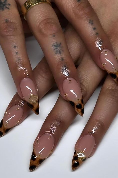 These elegantly pointed nails feature a chic nude base with striking tortoiseshell tips. Each nail is further accentuated with delicate gold foil accents, adding a touch of luxe to the design. Perfect for anyone seeking a sophisticated yet bold manicure. ✨  // Photo Credit: Instagram @nailsbyskyelinh French Black Almond Nails, Square Black And Gold Nails, Pointed Almond Nail Designs, Nude Almond Nails With Gold Design, Tortoise Shell Nails Stilleto, Almond Cute Nails Design, Black And Gold Nail Inspo Short, Tortoise Square Nails, Leopard Nail Tips