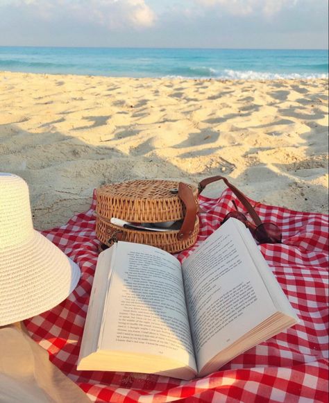 At the beach on the sand: a red and white gingham picnic cloth on top of it an open book, an open basket material crossbody bag coming out of it pens, and a white jute hat next to them with the sea in the background Reading On The Beach Aesthetic, Books On The Beach, Read On The Beach, Reading On The Beach, Beach Book, Beach Books, Sea Photography, Beach Cafe, Book Cafe