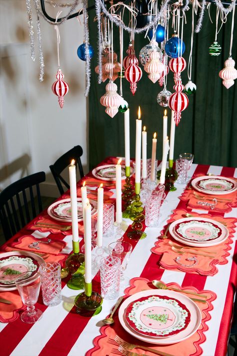 Funky candlesticks and colorful holiday plates sit atop a beautiful oversized circus stripe tablecloth creating the perfect colorful retro maximimal Christmas tablescape. Add scalloped placemats, gold silverware, and easy DIY place cards and you have the perfect party-ready holiday tablescape. #christmastabledecorations #colorfulchristmas #retrochristmas #bhg Retro Christmas Table, Holiday Tablescapes Christmas, Tablescapes Christmas, Halloween Christmas Tree, Diy Place Cards, Gold Silverware, Vibrant Decor, Vintage Christmas Wrapping Paper, Holiday Plates