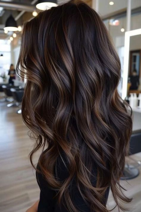 Long, wavy brown hair with caramel highlights in a modern salon setting. Dark Hair W Caramel Highlights, Black Hair Mocha Highlights, Black Hair Chocolate Balayage, Toning Highlights Darker, Highlights For Dark Brown Hair To Blend Gray, Dark Brunette Lowlights, Brown And Black Balayage, Black Hair With Brown Lowlights, Shades Of Brown Hair Color Chart