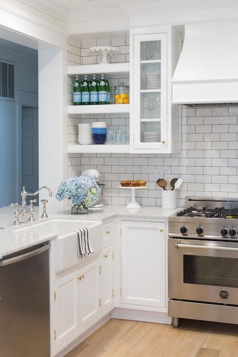 Gorgeous u-shaped kitchen features a pass through positioned above a peninsula fitted with white shaker cabinets donning brass hardware and gray and white quartzite countertop finished with a farmhouse sink and a polished nickel vintage deck mount faucet located next to a stainless steel dishwasher. Kitchen Layout U Shaped, Galley Kitchen Renovation, Small U Shaped Kitchen, Küchen In U Form, Kitchen Peninsula, Galley Kitchen Remodel, Budget Kitchen Remodel, Farmhouse Kitchen Remodel, Kabinet Dapur