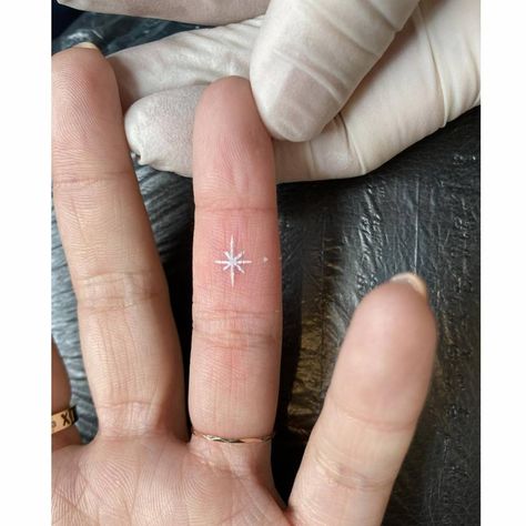 Small White Finger Tattoos, White Star Tattoos For Women, White Sparkle Tattoo, Tiny Starburst Tattoo, Tiny North Star Tattoo, White Tattoo Finger, White Ink Star Tattoo, Small White Tattoo For Women, White Ink Tattoo On Black Skin