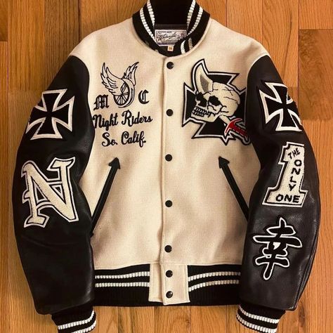 This varsity jacket is a striking blend of vintage and edgy styles, featuring a cream-colored wool body and black leather sleeves. The design is highlighted by bold embroidered patches, including a skull with a horn, "Night Riders So. Calif," and various symbols like the Iron Cross and a Japanese kanji for "happiness." The black and white striped ribbed cuffs, collar, and hem add a classic touch to this statement piece, making it a must-have for anyone looking to stand out. #VarsityJacket #... Letterman Jacket Ideas, Cream Varsity Jacket, Black And White Varsity Jacket, Iron Cross, Varsity Jackets, Japanese Kanji, Leather Sleeves, Custom Jacket, Letterman Jacket