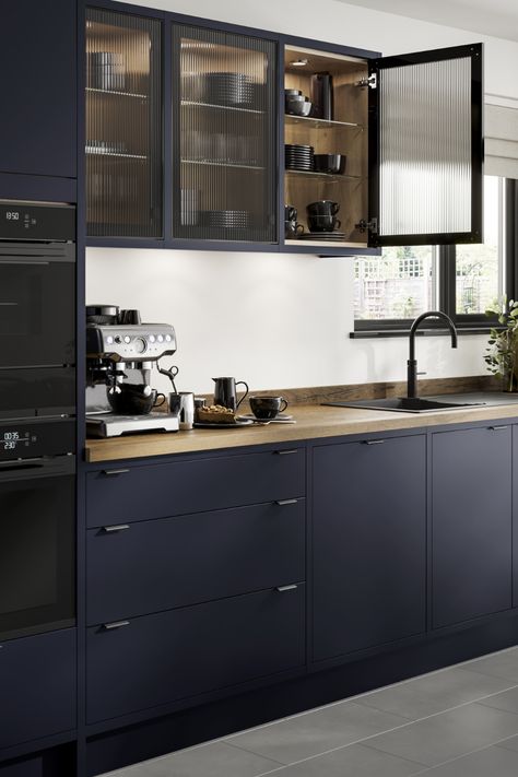 Looking for blue kitchen inspiration? Our Howdens Hockley Super Matt Navy In-Frame Kitchen is perfect for your blue kitchen ideas. The oak worktop, matt black tap and fluted glass kitchen doors are perfect for creating a navy kitchen design. Add your favourite home decor and kitchen appliances. Blue Black Kitchen Cabinets, Matt Blue Kitchen, Kitchen Glass Cupboards, Modern Navy Blue Kitchen, Black Kitchen Glass Cabinets, Black Kitchen With Glass Cabinets, Small Navy Blue Kitchen, Kitchen Black Glass Cabinets, Navy Kitchen Modern