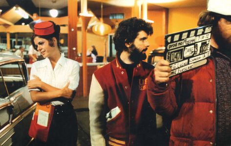 On the set of "American Graffiti", 1973.  L to R: Jana Bellan, co-writer/director George Lucas.  After the box-office disappointment of "THX-1138" (1971), Lucas focused on stories from his days growing up in Modesto, CA.  No studio wanted to take a chance except Universal on the strict condition it was shot for a low budget.  It cost $775,000 to produce, earned over $200 million - making it one of the most profitable movies of all time - and gave Lucas the clout to create "Star Wars". Car Movie, Car Hop, Movie Production, American Graffiti, Sock Hop, 32 Ford, Teen Movies, American Freedom, Film Studies