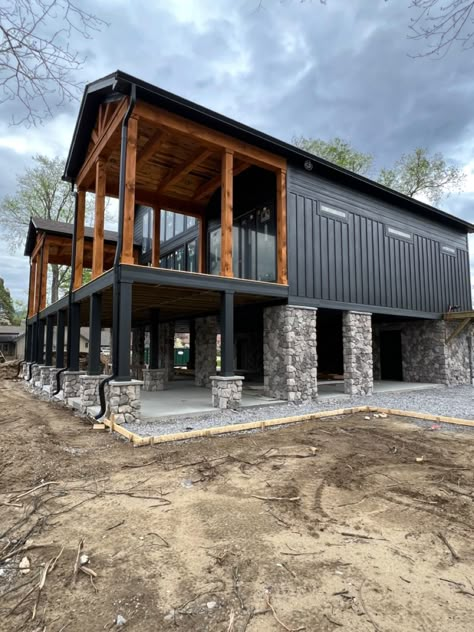 The contrast between the stonework, the siding color, the trim stain is Stunning Benjamin Moore Black Satin, Dark Barndominium, Benjamin Moore Black, Metal Building Designs, Cabin Renovation, Black Houses, Color Tips, Barn House Design, River Cabin