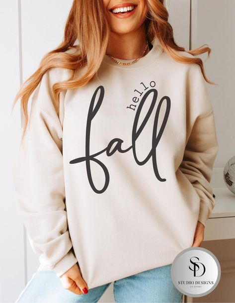 Welcome the crisp autumn air with this cozy Hello Fall Women Gildan Crewneck Sweatshirt! This soft and comfortable pullover is perfect for chilly days and everything you love about the season--pumpkin spice, falling leaves, and warm bonfires. Whether you're sipping hot cocoa or strolling through a pumpkin patch, this sweatshirt will keep you warm and stylish. Made from high-quality material, it's the perfect addition to your fall wardrobe. Material: Gildan cotton blend Fit: Unisex sizing, comfy fit Design: "Hello Fall" printed in a modern, seasonal font Occasions: Fall festivals, Thanksgiving gatherings, cozy nights at home, or casual outings Gift Ideas: Great for autumn lovers, cozy season enthusiasts, and fall fashionistas! Care instructions: * Wash items inside out in cold water. * Do n Thanksgiving Sweatshirt Ideas, Fall Sweatshirt Ideas, Fall Crewneck, Fall Festivals, Crisp Autumn, Pumpkin Spice Season, Cozy Season, Fall Clothing, Falling Leaves