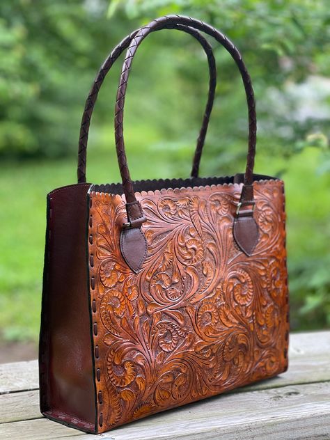 "Hand-Tooled Leather Tote Bag \"JOANA\" by ALLE, is your ultimate travel companion, made with full-grain hide, deeply embossed design on both sides of the bag, and beautiful hand-stitched adorning the sides of the bag. With a spacious interior and thoughtfully placed pockets, the Joana tote is ideal for everyday life. Perfect as a gift. Made from Full-grain leather, each bag varies in shading due to the thickness which is determined by the age of the animal and the natural creases of the leather Western Bags Purses, Tooled Leather Handbags, Western Bag, Expensive Bag, Vintage Leather Handbag, Tooled Leather Bag, Tooled Leather Purse, Work Handbag, Embossed Design