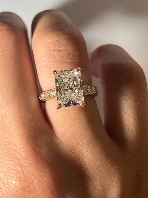 Our Juliana Engagement Ring features a breathtaking radiant cut diamond crafted in 18K yellow gold. This stunning center diamond is accentuated by a hidden halo and diamond prongs, adding a touch of mystique and enhancing the diamond's sparkle. The band is adorned with a three-row pavé setting, ensuring that every angle glistens with the brilliance of meticulously set smaller diamonds. Setting costs only. Refer to diamonds tab to choose your diamond Please allow 3-4 weeks for production. Different Shapes Of Engagement Rings, Gold Ring Marriage, Radiant Cut Engagement Ring With Band Gold, Emerald Shape Engagement Ring Gold, Square Diamond Ring Gold, Gold Engagement Rings Rectangle, Radiant Cut Engagement Ring Yellow Gold, Gold Band Big Diamond Engagement Ring, Different Carat Sizes On Hand