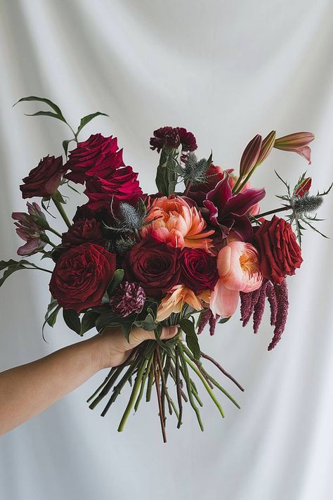 A burgundy bridal bouquet with red roses and dark amaranthus. Wedding Flowers Dark Red, Maroon Wedding Bouquet Burgundy, Modern Red Wedding Flowers, Burgundy And Red Wedding, Wedding Deep Red, Pink And Red Flowers Wedding, Red And Green Wedding Colors, Moody Fall Bridal Bouquet, Coral And Burgundy Wedding