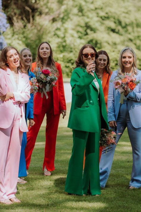 6 bridesmaids playing outdoor garden games in colourful suits. Pink, blue, red, green, orange and light blue Non Formal Wedding Attire, Bridal Party In Suits, Bridesmaid In Suits, Pant Suit Bridal Party, Bridesmaid In Suit, Wedding Guest Dress Colorful, Fun Wedding Outfits, Colorful Fun Wedding, Multi Coloured Bridesmaids