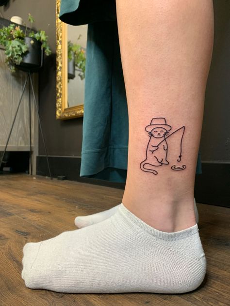 Lower leg tattoo of a cat wearing a hat fishing from a small puddle Cat Tattoos Funny, Minimalist Funny Tattoo, Funny Men Tattoo Ideas, Silly Fine Line Tattoo, Cat Tattoo On Leg, Silly Line Tattoos, Cat Fishing Tattoo, Small Silly Tattoos For Women, Goofy Cat Tattoo