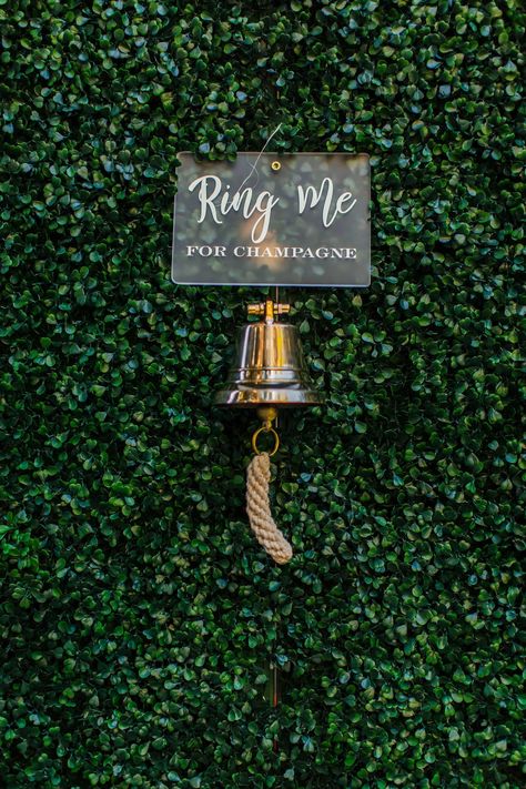 As guests arrived, they approached a large hedge wall and rang a bell to prompt a gloved hand to reach through the wall and hand them a glass of Champagne. Champagne Sign, Houdini Estate, Hedge Wall, Tent Event, Champagne Wall, Company Anniversary, Magical Decor, Selfie Wall, 2025 Wedding