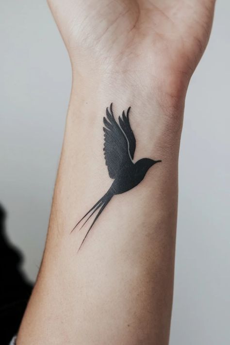 Silhouette of a bird tattooed on a forearm. Watercolor Bird Tattoos For Women, Black And White Bird Tattoo, Black Hummingbird Tattoo, Black Birds Tattoo, Small Wrist Tattoo Ideas, Women Tattoo Inspiration, White Bird Tattoos, Bird Silhouette Tattoos, Small Wrist Tattoo