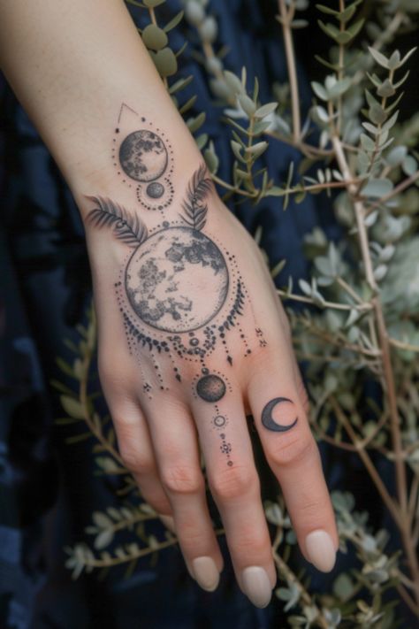 Intricate moon phase tattoo with celestial patterns on a hand surrounded by foliage. Celestial Hand Tattoos For Women, Planet Hand Tattoo, Viking Hand Tattoos For Women, Hand Tattoos Moon, Space Hand Tattoo, Hand Tattoos For Women Unique Ideas, Witchy Finger Tats, Unique Finger Tattoos For Women, Celestial Hand Tattoo