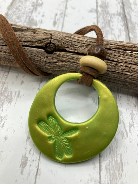 This is a 1 1/2 inch x 1 1/2 inch lightweight Pendant made with Candy Apple Green Premo polymer clay. Stamped by hand using gold mica powder to shine. It has 20 inch tan Leather cord, lobster claw clasp, and decorative bead.  Bead will vary in color/shape from bead pictured in product photo. This necklace is fully hand made and hand finished so slight variations in color/finish should be expected. Mica Powder color will shine differently in different light. Bohemian Clay Jewelry, Clay Pendant Necklace, Clay Pendants Diy, Dragonfly Clay, Pottery Pendants, Firefly Charm, Clay Necklace Pendant, Candy Apple Green, Clay Necklaces