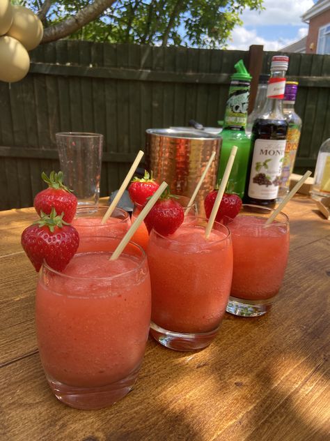 5 glasses of frozen strawberry daiquiri cocktail with straw straws and strawberries on the side. Ready on a wooden mobile bar in the garden Drink Bar Party Ideas, Cocktail House Party, 30th Birthday Garden Party, Fairy Cocktails, Cocktail Making Party, Garden Party Bar, Garden Cocktail Party, Garden Party Drinks, Garden Drinks