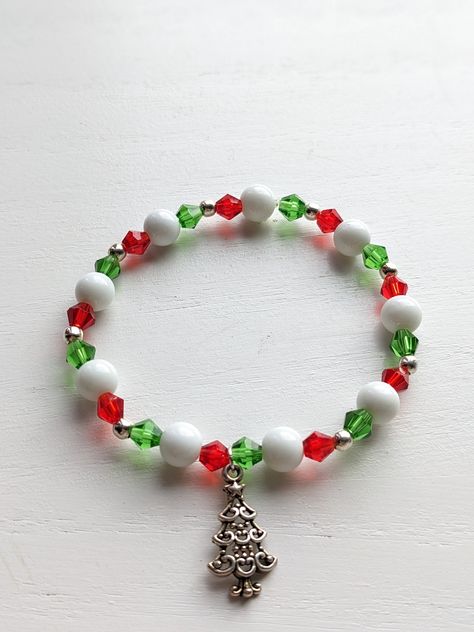 Handmade stretchy beaded Christmas charm bracelets. Perfect to add a little cheer to your holiday outfit. Makes a great gift. Comes with either a red or green assorted mesh gift bag. These ready to ship handmade bracelets are sized at 7 1/2 inches. The perfect gift How to order: Choose your bracelet type from drop down menu. The photo will auto to the type of bracelet. Choose the type you would like to order and check out. How to Measure Your Wrist:  take a flat tape measure and measure around your wrist in inches, where you wear the bracelet. If you want the bracelet to be snug/tight excat inches. If you want it to be a little lose  size up to a half-to full inch. Christmas Stretch Bracelets Ideas, Holiday Beaded Bracelets, Christmas Beaded Jewelry, Christmas Beaded Bracelets, Christmas Bracelet Ideas, Holiday Jewelry Ideas, Beaded Decorations, Handmade Bracelets Tutorial, Bracelets Christmas