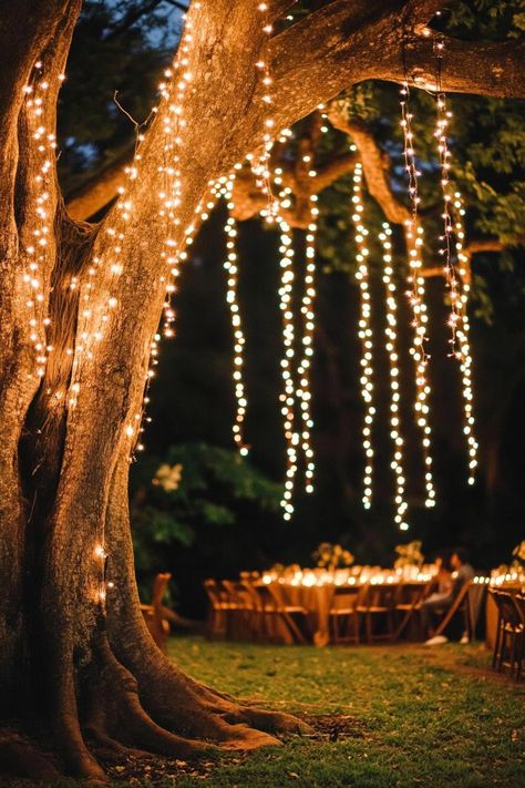 Enchanted forest theme wedding decor outdoor big tree with thousands of hanging fairy lights nighttime soft glow of fairy lights. Let your big day become a magical woodland affair with these enchanting forest wedding ideas that’ll make your guests feel like they’ve stepped into a fairy tale. Magical Garden Party, Tree Decorations Wedding, Tolkien Wedding, Hanging Fairy Lights, Mystical Wedding, Main Table Wedding, Forest Wedding Reception, Forest Wedding Theme, Enchanted Forest Birthday Party