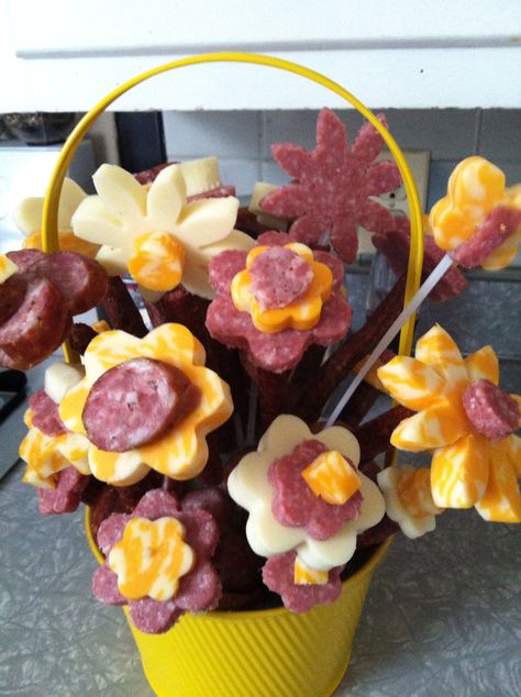 Instead of the typical fruit bouquets, we did a meat one for my mother in law for Mother's Day. Use plastic flower picks, cover with smoked jerky as the stems, use slices as "mulch". Finally use metal shapes to create the flowers. Make sure you refrigerate!! Flowers Made From Food, Mothers Day Gift Ideas For Mother In Law, Meat Flowers Diy, Flower Snack Ideas, Flower Shaped Appetizers, Meat And Cheese Bouquet, Flower Shaped Snacks, Flower Themed Party Food, Fruit Flower Bouquet