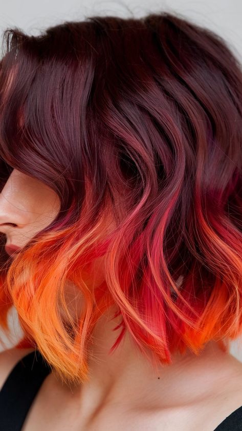 Discover the beauty of layered curls with this stunning hair color that blends rich burgundy and eye-catching orange. This hairstyle is all about fun and flair, perfect for those who love to express their creativity through their look. Elevate your hair game with this vibrant masterpiece! #haircolor #hairstyle #hairideas #hairinspo #fallhair Orange And Brunette Hair, Purple To Orange Hair, Sunset Peekaboo Hair, Sunset Balayage Hair, Sunset Hair Color Short, Fire Hair Color Short, Flame Hair Color, Pink Color Block Hair, Fun Red Hair Color Ideas