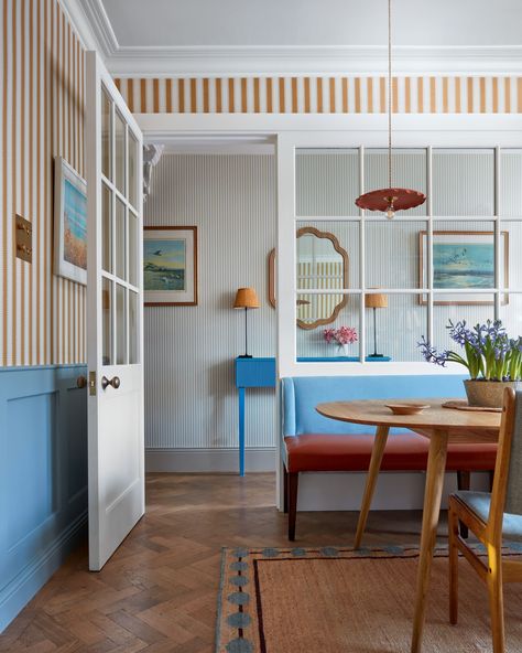 This townhouse was modernized by Laura Stephens with fresh colors, textures of jute and seagrass mixed with 20th-century architectural details. The effect is bright, comfortable and ageless. Laura designed the blue half panelling in the dining room as a foil for the janutily striped wallpaper, and in the kitchen a slice of wall was removed to insert a window into the sitting room, flooding the house with light throughout. . Photography by James McDonald Most Beautiful Houses, Interior Design Instagram, London Townhouse, Pierre Jeanneret, Colorful Home, Striped Wallpaper, Eclectic Home, Breakfast Nook, My Dream House