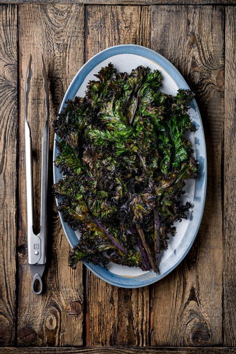 An oval plate with grilled kale on it. A pair of BBQ tongs on the left hand side of the plate Salad Citrus, Grilled Kale, Massaged Kale, Kale Leaves, Oval Plate, Kale Salad, Vegan Dinner, Grilled Vegetables, Garlic Salt