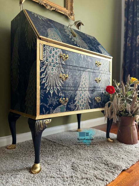 This stunning upcycled bureau features a captivating blue and gold peacock design, transforming it into a statement piece for any home office or study. The vibrant colors and intricate detailing of the peacock motif add elegance and sophistication, while the restored finish highlights the desk's timeless charm. With its blend of functionality and artistic flair, this writing desk not only provides a stylish workspace but also promotes sustainable living through its upcycled craftsmanship.this wa Decor Transfers For Furniture, Upcycled Bureau Ideas, Writing Bureau Upcycled, Bureau Upcycle Ideas, Painted Desks Ideas Colors, Peacock Furniture, Bureau Upcycle, Peacock Room Decor, Furniture Recycle