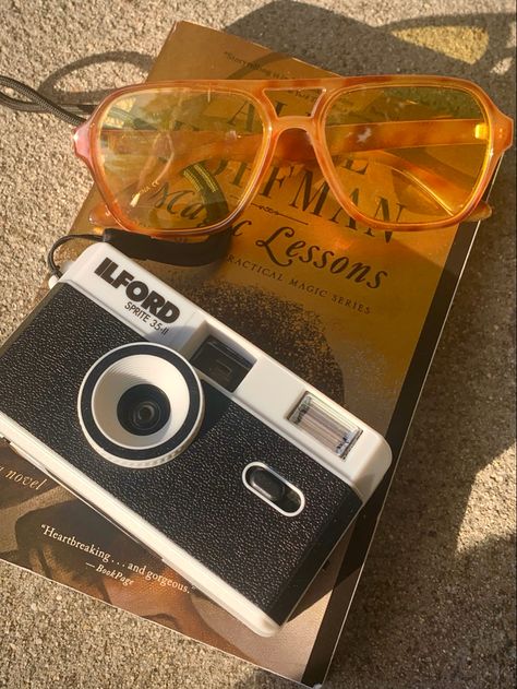 Tortoise shell aviator sunglasses with yellow yellow tinted glass and a black and white 35mm film camera on top of a copy of a gold and black book. Orange Camera Aesthetic, Yellow Science Aesthetic, Orange Sunglasses Aesthetic, Yellow Camera Aesthetic, Aviators Aesthetic, Aviator Sunglasses Aesthetic, Yellow Sunglasses Aesthetic, Aviator Glasses Aesthetic, 80s Film Camera