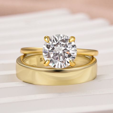 Ring information:         Metal:   925 Sterling Silver;      Plating Color:    18K Yellow Gold;       Rhodium:   Yes;      Nickel Free:    Yes;       Gem Information:         Gem Type:    Moissanite Stone;       Center Stone Shape:    Round Cut(8 mm);      Center Stone Color:   White Stone;     Center Stone Weight:   2.0 Carat;       Band Stone Color:   White Stone;       A Bold Statement of Everlasting Love Striking, sophisticated, and truly unforgettable  The Moissanite 2.0 Carat Round Cut Yellow Gold Wedding Ring Set With Wide Wedding Band is designed for those who love a touch of grandeur. Featuring a breathtaking 2.0-carat round-cut moissanite center stone, the engagement ring is complemented by a wide, shimmering wedding band that enhances its brilliance. Crafted in 925 sterling silv Wide Wedding Bands, Everlasting Love, White Stone, Wedding Ring Sets, Ring Sets, Stone Color, Round Cut, Wedding Bands, Wedding Rings