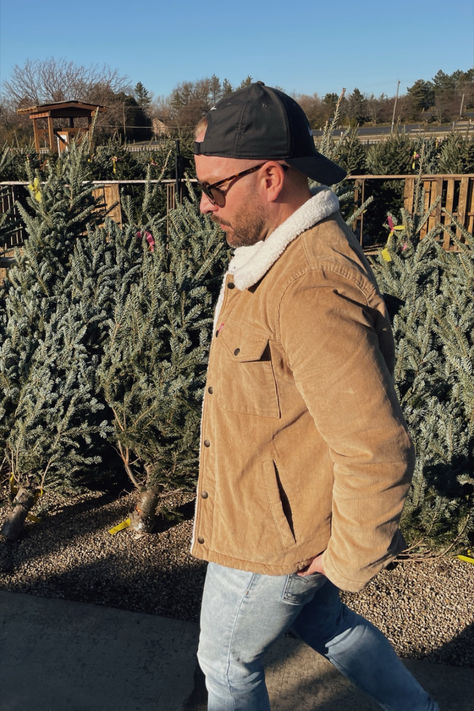 Man walking in front of a row of fresh cut christmas trees wearing a tan corduroy jacket, light wash jeans and a backwards black hat. Street Fashion Men Streetwear, Men Streetwear, Winter Outfits Men, Trucker Jacket, Basic Tee, In The Winter, Mens Streetwear, Men Winter, Winter Outfit