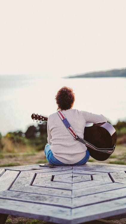 A Back View of a Person Sitting while Playing Guitar · Free Stock Photo A Person Sitting, Guitar Posters, White Long Sleeves, Ganesha Art, Board Inspiration, Person Sitting, Back View, Sit Back, Playing Guitar