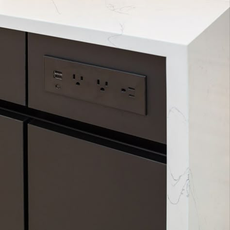 The kitchen island has a built in outlet with USB ports for charging devices. Black cabinets with white quartz waterfall countertop Island Outlets Kitchen, Kitchen Island Outlet Ideas, Kitchen Island Outlets, Outlets In Kitchen Island, Kitchen Island Outlet, Kitchen Countertop Decor Ideas, Kitchen Gadgets Storage, Countertop Decor Ideas, Kitchen Outlets