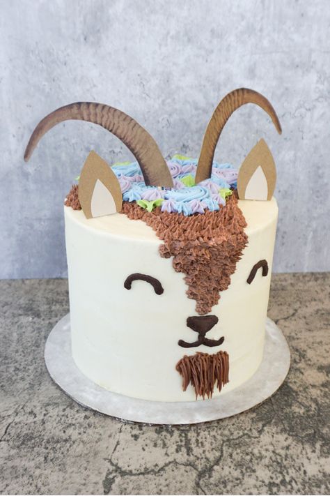 I make this adorable goat cake for an Easter gathering! It was made with carrot cake and vanilla frosting, with some chocolate frosting decorations. The flowers and leaves on top were made with natural food coloring, and the ears and horns are custom toppers that I made!   #customcake #goatcake #naturalfoodcoloring #chocolatefrosting #vanillafrosting #carrotcake #goats #goat #mtnsidebakery #cakedecorating #cakeideas #birthdayideas #birthdaycake #kidsbirthday #birthdayparty Goat Party Ideas, Goat Party Theme, Goat Cupcakes, Goat Cake Ideas, Lamb Cake Ideas, Goat Birthday Party, Goat Cake, Goat Party, Cake Sculptures