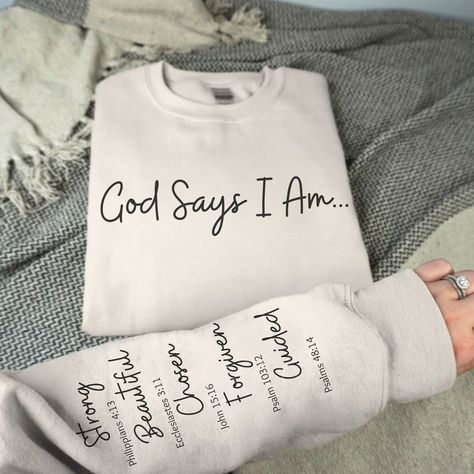 Introducing our Unisex God Says I AM sweatshirt, a cozy and stylish expression of faith. Crafted with comfort in mind, this sweatshirt features a unique design: God Says I am, printed on the front. The left sleeve displays a list of what God says we are and the bible verse associated with each quality and adjective, a powerful reminder of what we represent to God. Let this be your pick-me-up, motivational sweatshirt and a beautiful reminder to anyone who comes across it. Made from premium materials, this sweatshirt not only provides warmth but also serves as a wearable testament to your Christian values. Embrace the fusion of fashion and faith with this meaningful garment that allows you to carry your spirituality with you wherever you go. Choose Color and Size from the menu. Our unisex he God Says I Am Shirt, Christian Clothing Ideas, Bible Verse Shirts For Women, God Says You Are, God Says I Am, Cute Christian Sweatshirts, Christian Vinyl Shirts, Christian Athletic Apparel, Christian Sweatshirt Designs