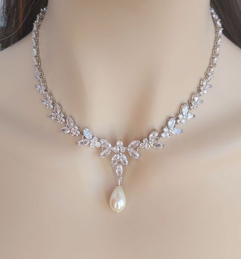 ❤️ Best seller! Luxurious and eye catching V shape bridal necklace (and earrings optional) designed to be delicate and feminine. This bridal necklace is made with marquise cut, clear Cubic Zirconia in silver-platinum plated \settings forming a floral, leaf motifs. This timeless jewelry is very elegant and sparkles beautifully catching and reflecting the light. - Necklace length: 17 inches long (please, contact me for a longer necklace) The necklace closes with an easy to manipulate silver plated foldover clasp. *The necklace can also be made without the CZ drop dangling bellow. - Earrings length: 30mm longme and dangle from CZ set stud ear posts. Matching bracelet: https://www.etsy.com/listing/859475493/silver-bridal-bracelet-crystal-wedding?ref=listing_published_alert https://www.etsy.com Silver Earrings And Necklace, Light Jewellery Designs, Light Necklace Designs, Bridal Necklace Set Weddings, Bride Accessories Jewelry, Brides Necklace, Bridal Jewelry Silver, Necklace For Bride, Pearl Wedding Jewelry Sets