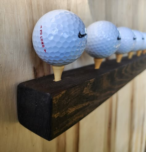 Check out this awesome flush mount wall golf ball holder. This wood stained piece has 7 built in tees to set some of your favorite golf balls out to be on display. The bar sits flush with the wall using keyhole mounts. This is a great way to show off your collection on a floating shelf. Thank you for visiting 2nd Life Golf! Golf Office Decor Ideas, Golf Storage, Golf Decorating Ideas Interior Design, Golf Club Wall Display, Hole In One Golf Ball Display, Golf Memorabilia Display, Golf Ball Display, Display Golf Balls, Golf Ball Holder Display