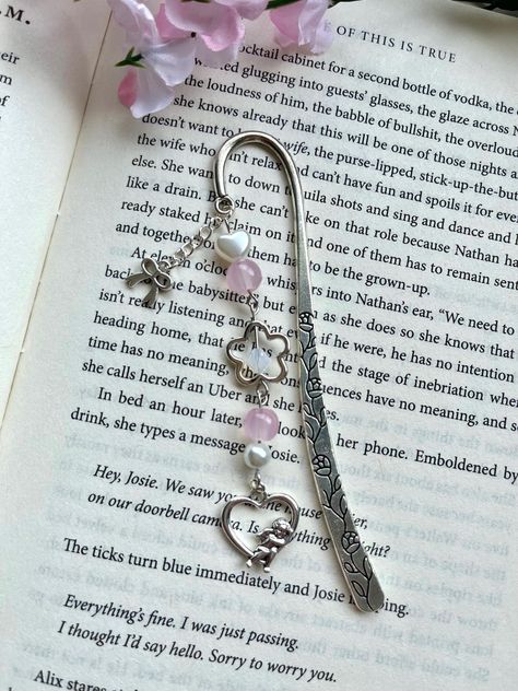 Handmade beaded bookmark featuring a coquette theme! Materials used include a silver metal bookmark hook, silver charms, and glass and plastic beads. Make your reading experience even cuter with this unique bookmark! ❀Canadian Customers- Standard default shipping ($2) *does not* include tracking as it is sent as untracked lettermail (via stamp). Upgraded shipping can be purchased at checkout, which includes tracking! Orders can take from 3-10+ business days to arrive if sent with standard shippi Bookmark Charms, Beads Bookmark, Bookmark Charm, Bookmarks Crochet, Coquette Theme, Silver Bookmark, Charm Bookmark, Heart Bookmark, Beaded Bookmarks